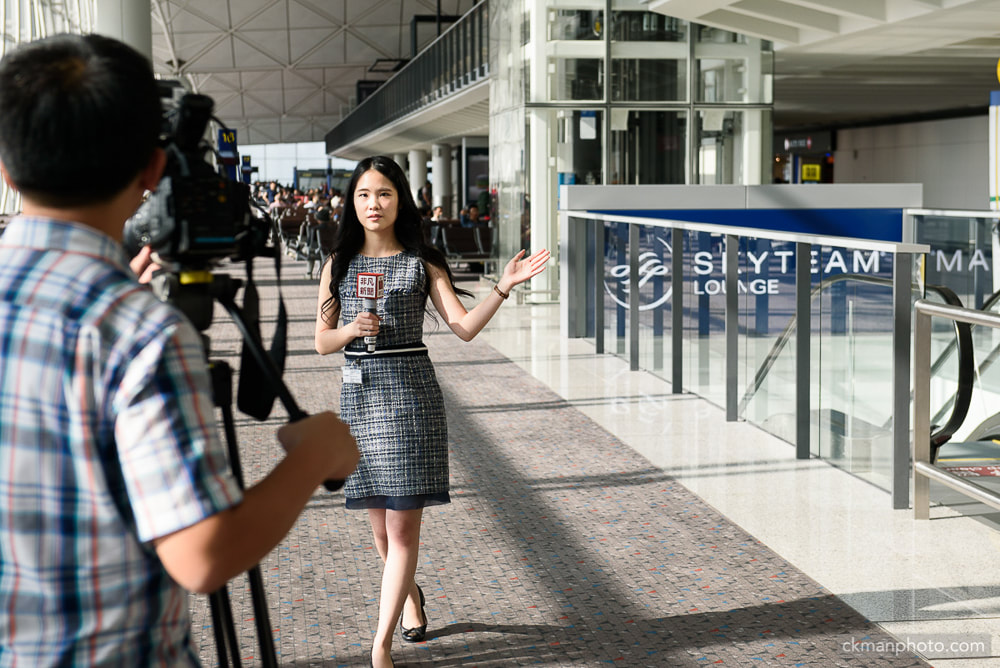 TV news reporter covering grand opening of Skyteam lounge in Hong Kong